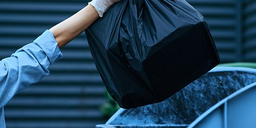 Valet trash service in South Florida: a porter collecting bagged trash from an apartment doorstep