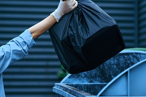 Valet trash service in South Florida: a porter collecting bagged trash from an apartment doorstep