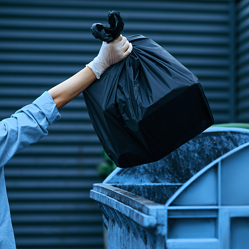 Valet trash service in South Florida: a porter collecting bagged trash from an apartment doorstep
